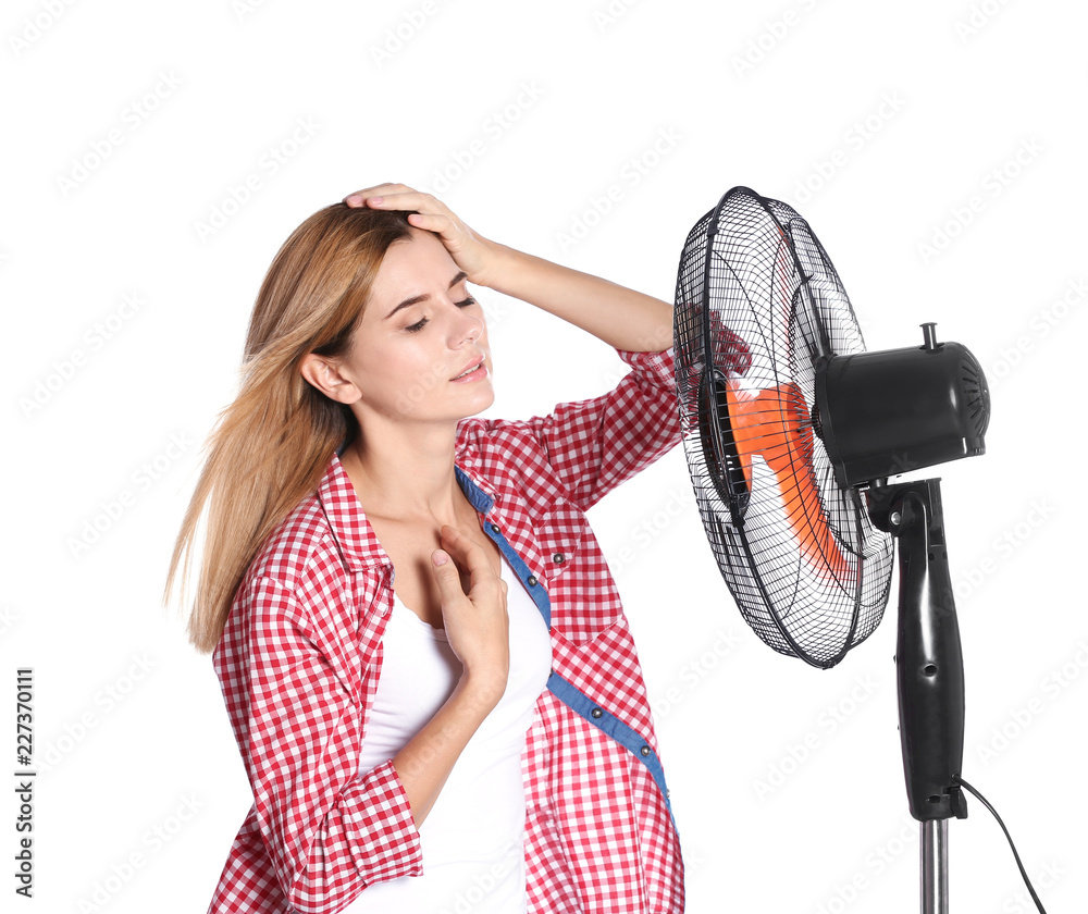 Poster woman suffering from heat in front of fan on white background