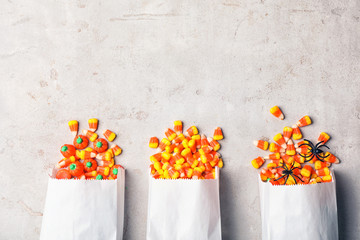 Flat lay composition with paper bags of delicious candies and space for text on gray background