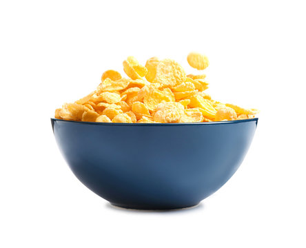 Crispy cornflakes falling into bowl on white background