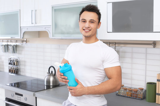 Man with bottle of protein shake in kitchen