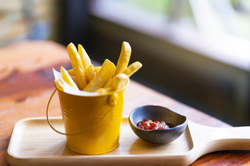 French fries and ketchup on wood board background.