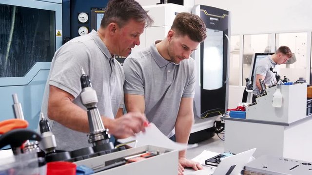 Engineer Showing Apprentice How Use CAD Software On Laptop 
