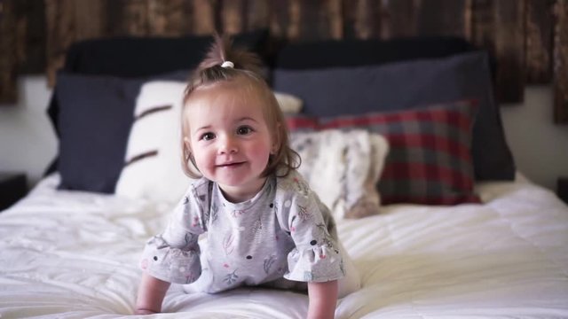 Cute little baby girl on bed at home