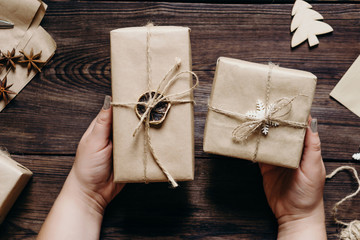 Preparing for Christmas. Female hands with decorated Christmas presents. Family celebration, joy, surprise, love concept. 