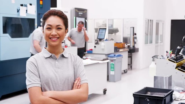 Portrait Of Female Engineer On Factory Floor Of Busy Workshop