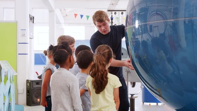 School kids using giant globe with teacher at science centre
