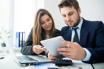 Young businessman discussing something with his colleague, and using a digital tablet together