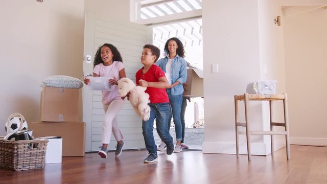 Slow Motion Shot Of Excited Family Carrying Boxes Into New Home On Moving Day