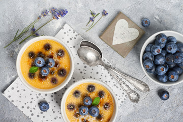 Creme brulee with blueberry andl avender powdered with sugar on light concrete background