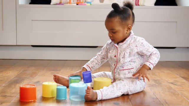 Female Toddler At Home Playing With Stacking Plastic Toy