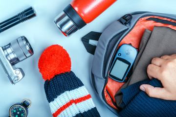 hand packing clothes in the backpack for travel with accessories, travel concept