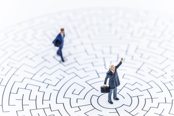 Miniature people Businessman standing on center of maze using 