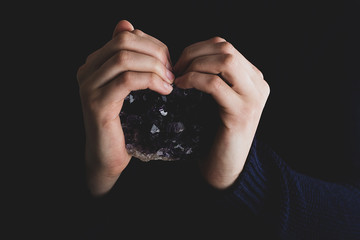 Hands holding purple amethyst crystal