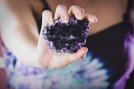 Hands holding purple amethyst crystal