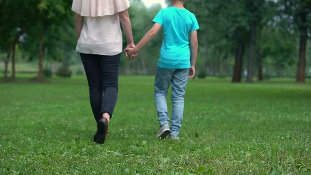 Mother and son holding hands, walking away together, concept of child adoption