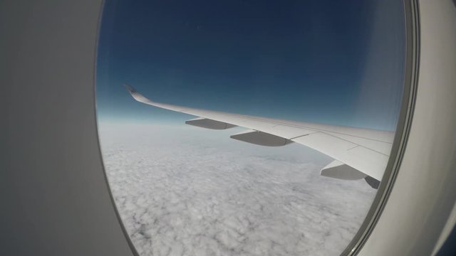 Aerial view. Looking out through an airliner window during daytime. View of an airplane wing high above clouds over North America en route from Denver, United States to Munich, Germany.