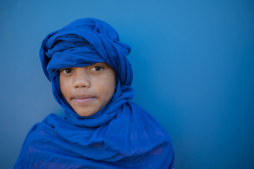 Portrait of boy with headscarf against blue background