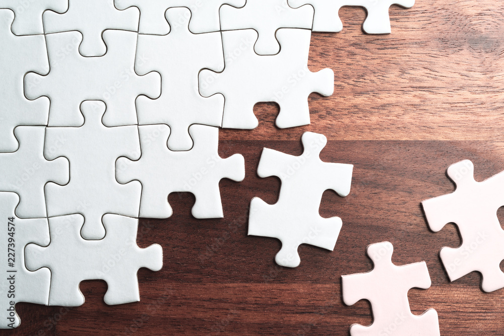 Poster assembling jigsaw puzzle pieces. abstract background.unfinished white jigsaw puzzle pieces on wood t