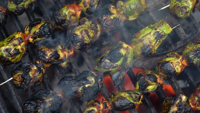 Overhead view of skewered brussels sprouts smoking on a hot grill.