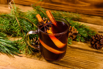 Cup of mulled wine with cinnamon and fir tree branches on wooden table