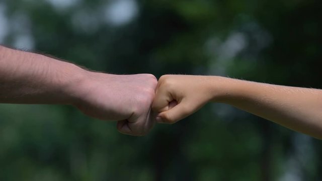 Man and child punching fists, parents as reliable support for children, closeup