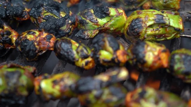 Closeup turning view of smoking, skewered brussels sprouts on a hot grill.