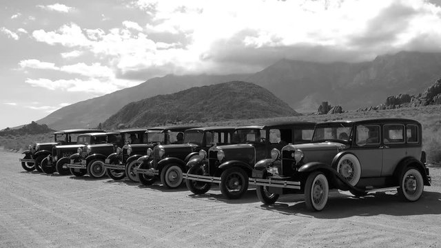 Several 1930 model A sedans in a row parked in the Alabama Hills Ca in black and white.