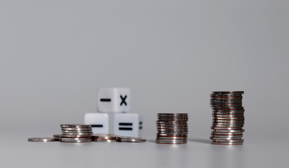 The pile of coins and three math symbol cubes.