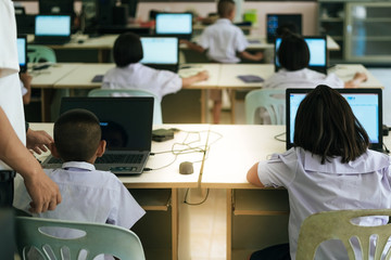 Primary Students study by computer in classroom.