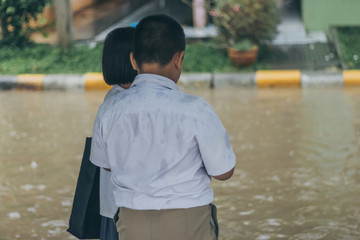 Boy and girl  wait to cross flooded street in heavy rainstorm be