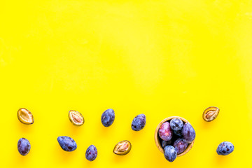 Blue plum for dessert. Purple plum and leaves pattern on yellow background top view copy space