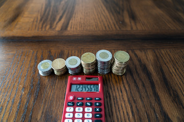 Red Pocket Calculator with Stacks of Coins in the background