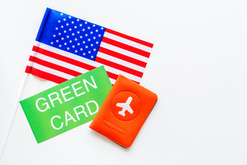 United States of America permanent resident cards. Immigration concept. Text green card near passport cover and US flag top view on white background space for text