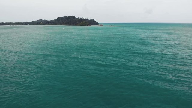 The camera flies above sea water to the mainland. Thailand