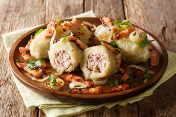 Lithuanian food: Cepelinai boiled potato dumplings with minced meat served with bacon, parsley and fried onions close-up. horizontal © FomaA