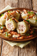 Cepelinai zeppelins or didzkukuliai is a traditional Lithuanian dish of stuffed potato dumplings close-up. vertical © FomaA