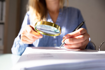 Businesswoman Checking Invoice With Magnifying Glass