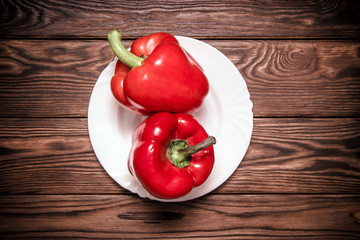 Two red peppers lying on a brown background 