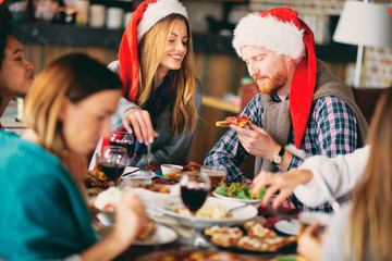 Friends having dinner at home at Christmas eve. Winter holidays concept.