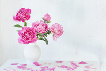 pink peonies in vase on vintage white wooden shelf