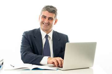 Attractive happy mature caucasian businessman working on laptop computer on desk at office