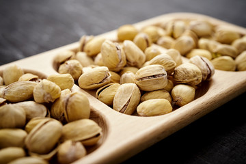 delicious pistachios on a wooden plate on an old black table in a pub