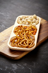 plate with delicious pistachio pretzels and peanuts on an old black wooden table in a pub