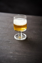 one glass of delicious beer on an old black wooden table in a pub