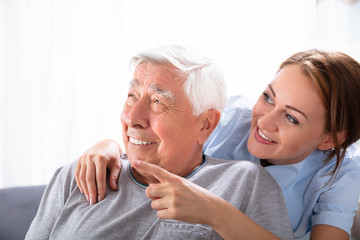 Nurse Pointing At Something To Senior Man