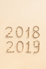 2018 and 2019 handwritten on the sand beach. New Year concept.