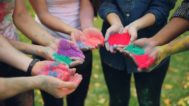 Close shot of people's hands holding colorful paint powder for Indian traditional Holi festival standing outdoors. National culture, fun and holiday concept.