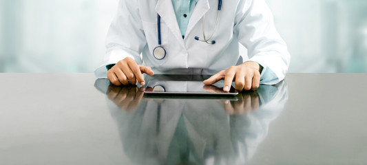 Male doctor sitting at table with tablet computer in hospital office. Medical healthcare staff and doctor service.