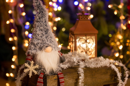 Christmas elf on a wooden bench and Christmas tree on background