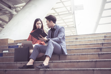 Young business man and woman use notebook laptop for work project in city.